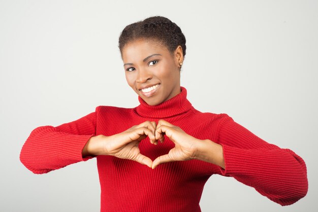 Souriante jeune femme montrant le signe de l'amour