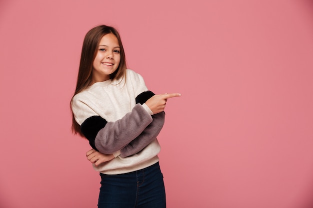 Souriante jeune femme pointant à l'espace de copie et à la recherche