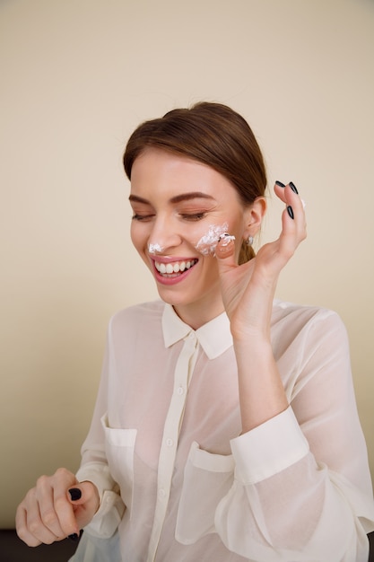 Souriante jeune femme posant en mangeant des cupcakes.