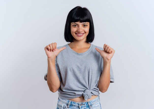 Souriante jeune femme de race blanche brune pointe sur elle-même