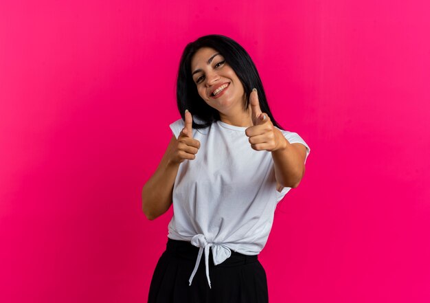 Souriante jeune femme de race blanche regarde et pointe la caméra à deux mains