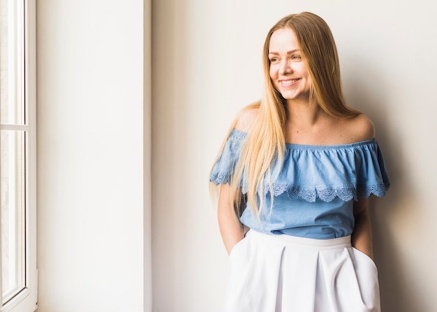 Souriante jeune femme regardant la fenêtre