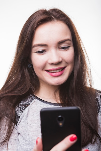 Souriante jeune femme regardant son smartphone