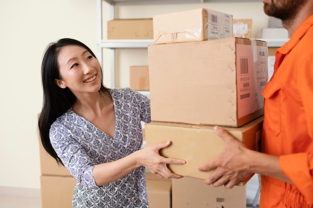 Souriante jeune femme remettant des boîtes de livraison au courrier