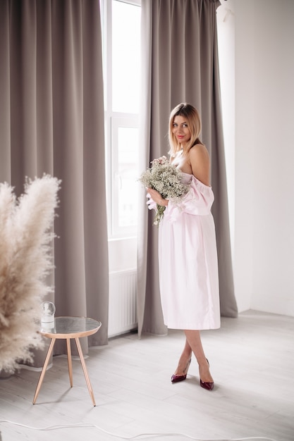 Souriante jeune femme en robe profitant de la journée avec des fleurs