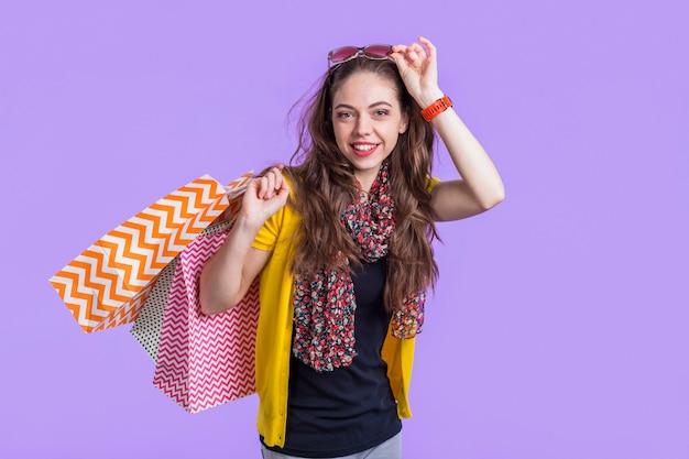 Souriante jeune femme avec des sacs à provisions sur fond violet