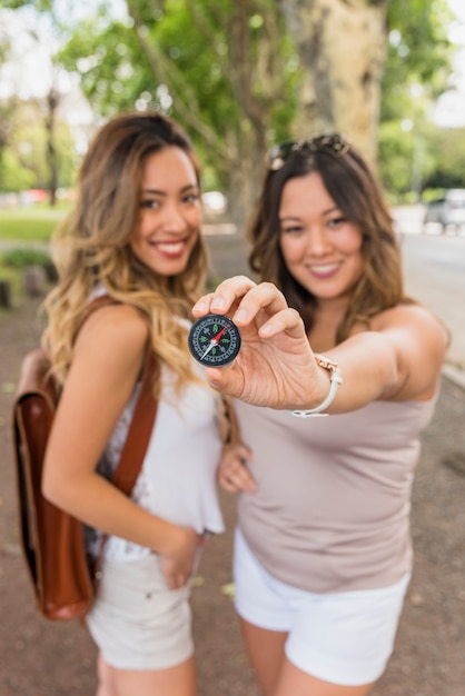 Souriante jeune femme avec son amie montre boussole