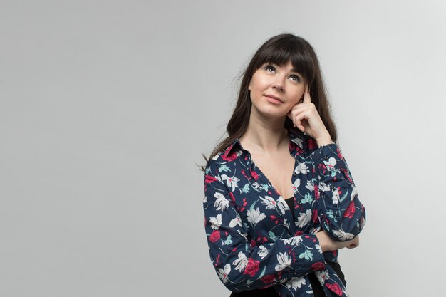 Souriante jeune femme en t-shirt conçu de bonne humeur aux cheveux longs sur blanc