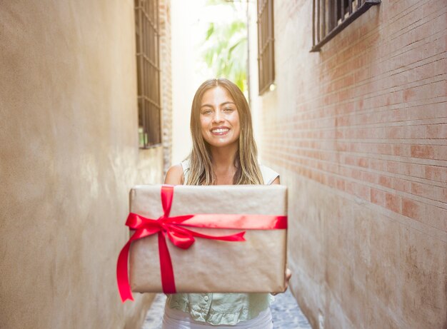 Souriante jeune femme tenant présent