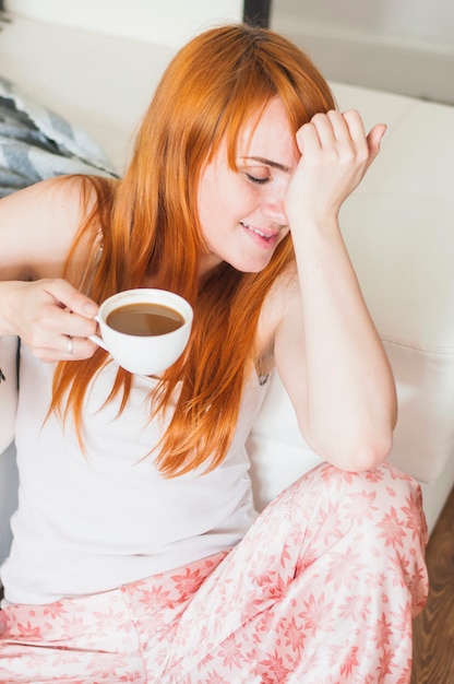 Photo gratuite souriante jeune femme tenant une tasse de café