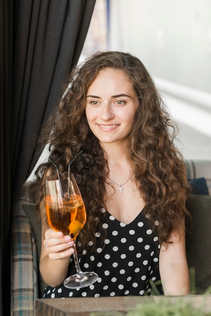 Souriante jeune femme tenant un verre à cocktail dans sa main