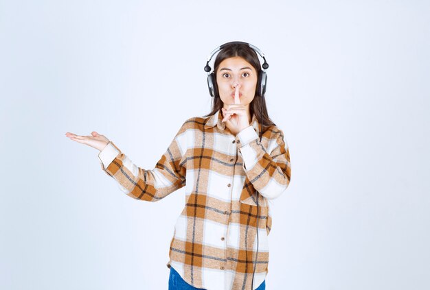 Souriante jeune fille au casque écoutant la chanson et donnant le signe du silence.