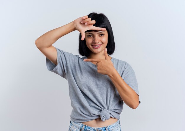 Souriante jeune fille brune caucasienne gestes cadre signe de la main