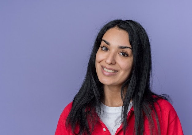 Souriante jeune fille brune caucasienne semble isolée sur un mur violet