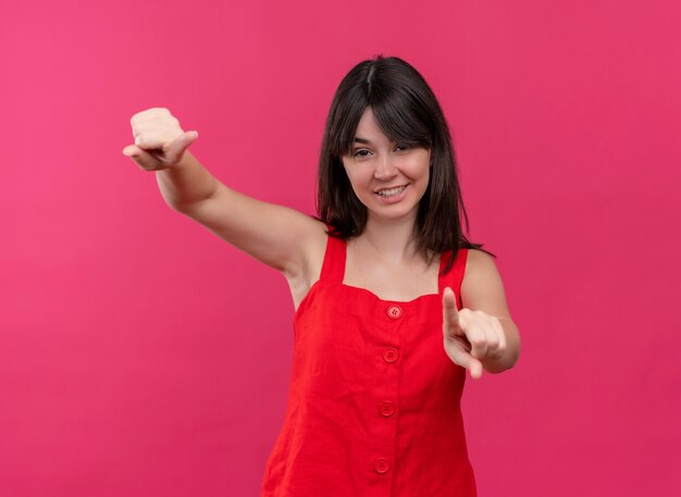 Souriante jeune fille caucasienne pointe vers l'avant avec les deux mains sur fond rose isolé