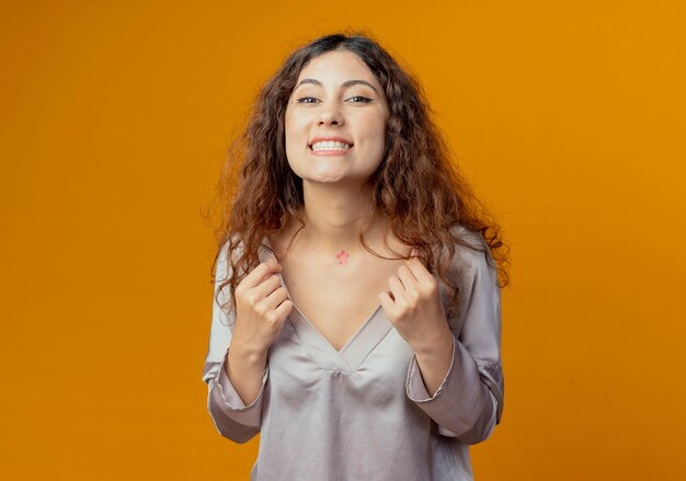 Souriante jeune jolie fille a attrapé le collier isolé sur jaune