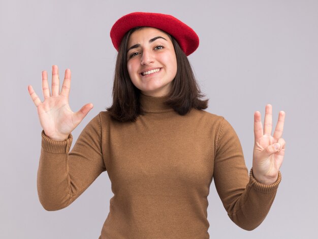 Photo gratuite souriante jeune jolie fille caucasienne avec béret faisant des gestes huit avec les doigts