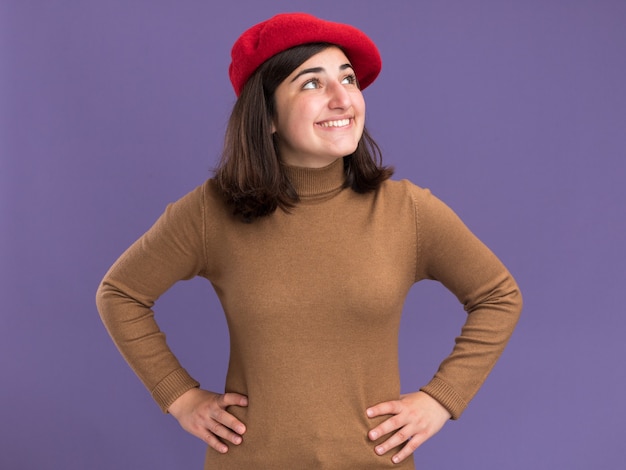 Souriante jeune jolie fille caucasienne avec chapeau de béret regardant de côté