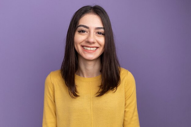 Souriante jeune jolie fille caucasienne isolée sur mur violet avec espace de copie