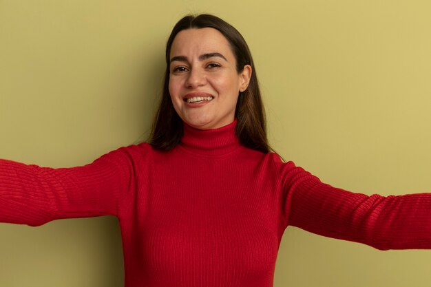 Souriante jolie femme caucasienne fait semblant de tenir la caméra sur vert olive