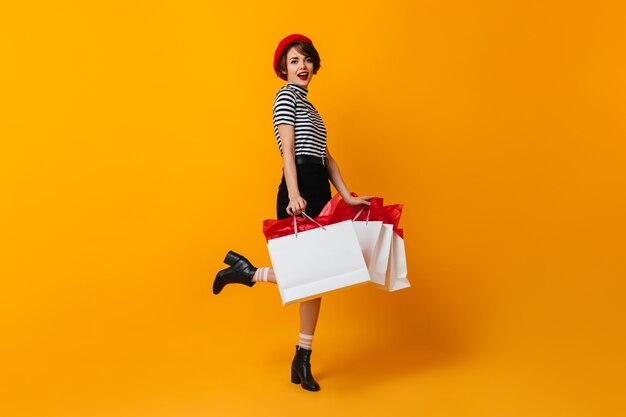 Sourire accro au shopping femme debout sur une jambe