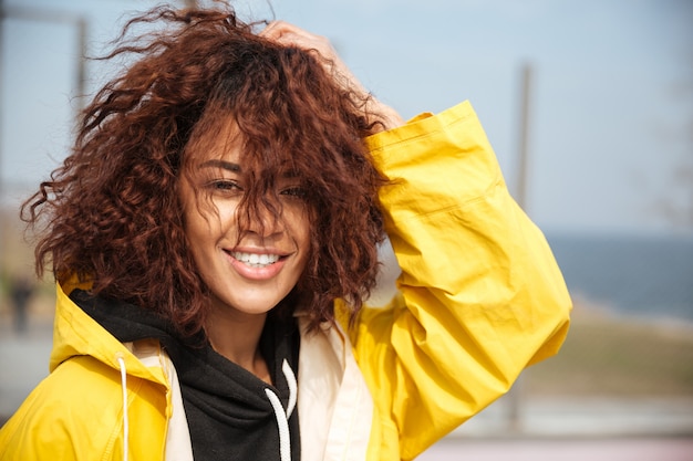 Sourire, africaine, bouclé, jeune femme, porter, manteau jaune