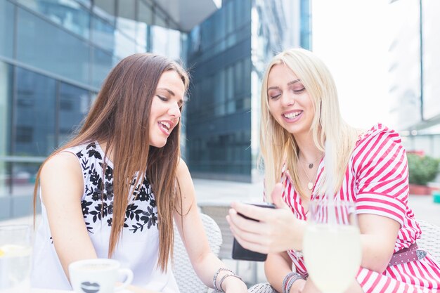 Sourire amies regardant téléphone mobile