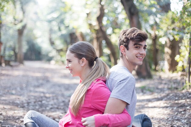 Sourire amis étirement ensemble assis dans le parc