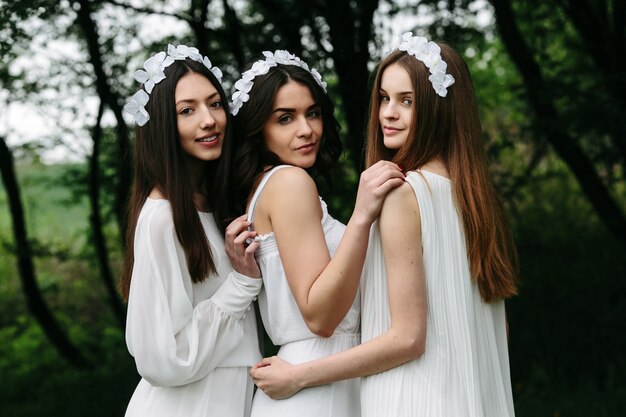 Sourire amis posant avec des couronnes de fleurs en plein air