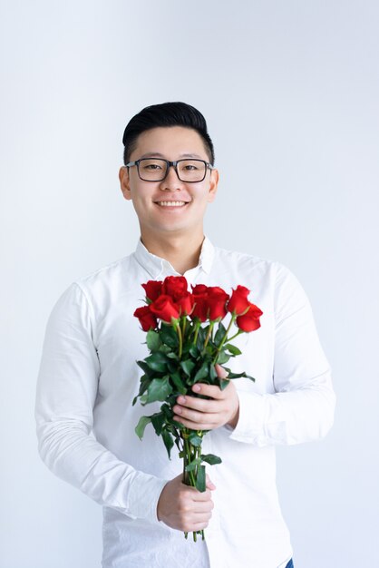 Sourire asiatique homme tenant un bouquet de roses