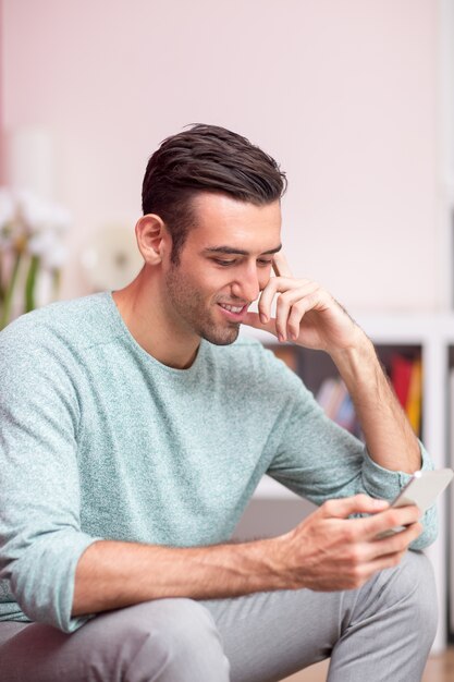 Sourire, attrayant, homme, utilisation, smartphone, maison