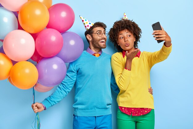 Sourire beau jeune couple lors d'une fête posant avec des ballons