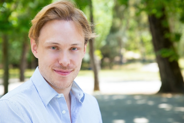 Sourire beau mec posant dans le parc