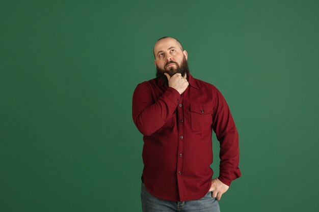 Le sourire. Beau portrait d'homme caucasien isolé sur mur vert avec fond. Modèle masculin élégant avec barbe. Concept d'émotions humaines, expression faciale, ventes, publicité, mode, jeunesse.