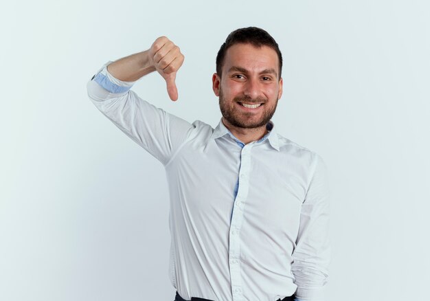 Sourire bel homme pouces vers le bas isolé sur un mur blanc