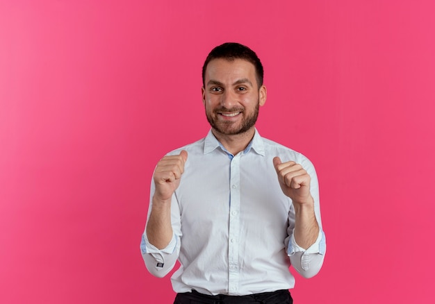 Sourire bel homme se montre avec deux mains isolé sur un mur rose