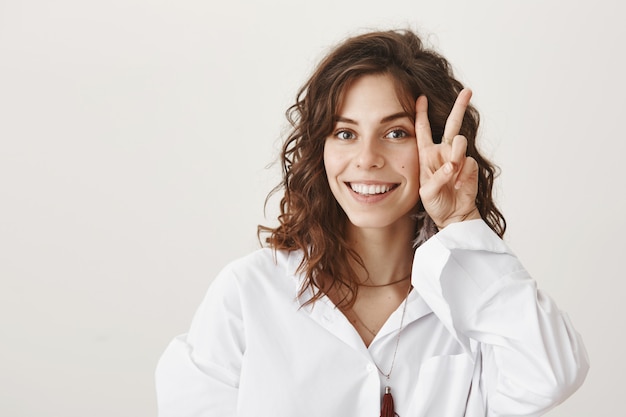 Sourire belle femme montrant un signe de paix près de son visage