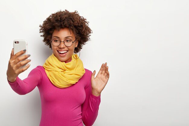 Sourire Belle Fille Afro Avec Des Cheveux Croquants, Paume Des Vagues à Huis Clos Du Smartphone, Fait Appel Vidéo