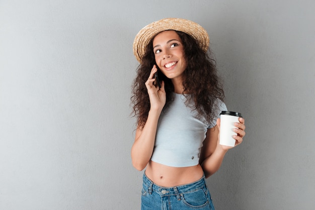 Sourire, bouclé, femme, chapeau, conversation, smartphone, café, main, regarder, haut, gris, fond