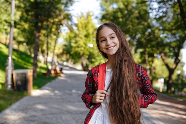 Sourire brune jeune fille posant dans le parc