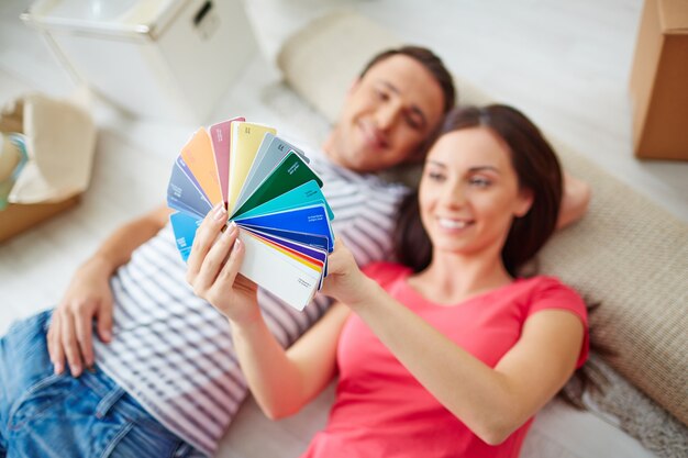 Sourire, couple, regarder des échantillons de couleurs à la maison