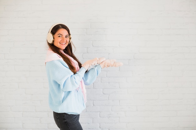 Photo gratuite sourire dame en mitaines, cache-oreilles et foulard à mains ouvertes