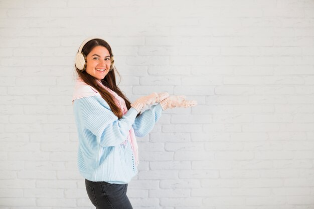 Sourire dame en mitaines, cache-oreilles et foulard à mains ouvertes