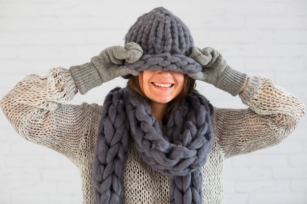 Sourire dame en mitaines, écharpe et bonnet sur les yeux