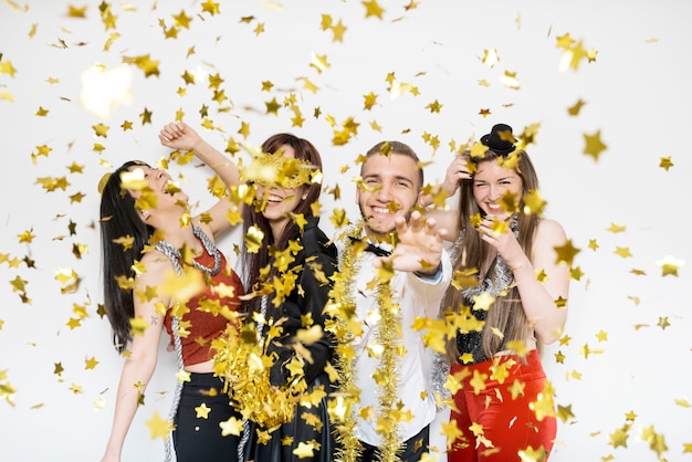 Sourire dames et gars en tenue de soirée entre confettis d&#39;ornement