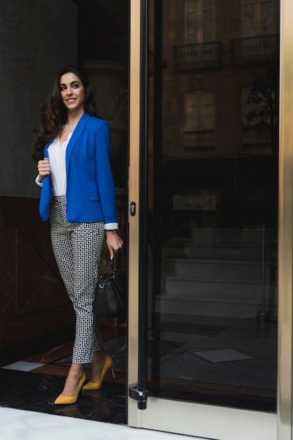 Photo gratuite sourire employé à côté d'une porte en verre