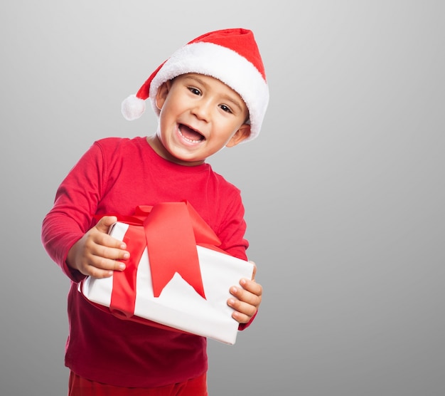 Sourire enfant tenant un cadeau avec un ruban décoratif