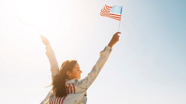 Sourire femelle élever les mains avec drapeau USA