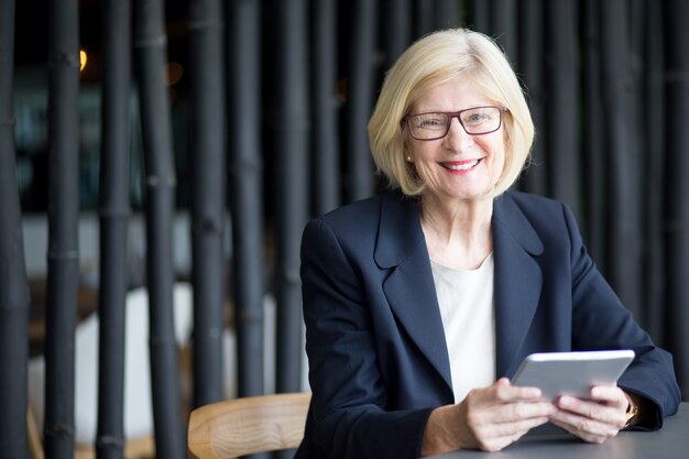 Sourire femme d&#39;affaires senior utilisant le pavé tactile