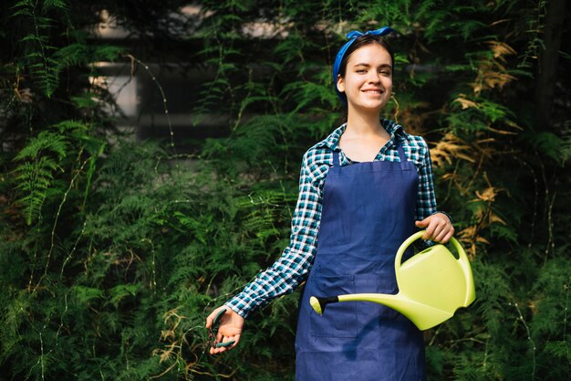 Photo gratuite sourire femme avec arrosoir élagage des plantes avec sécateur